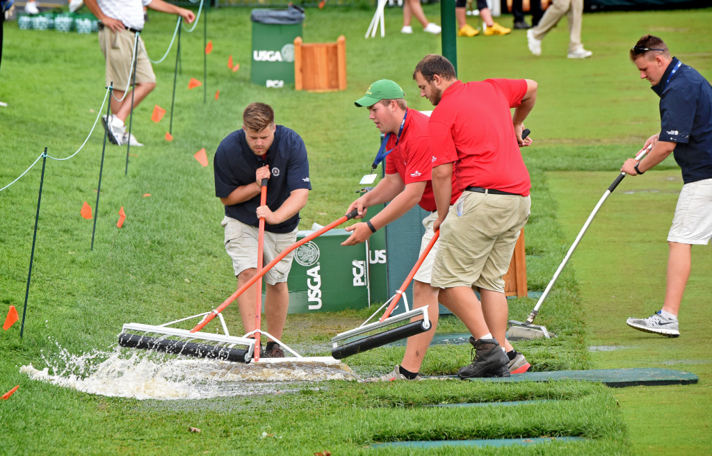 Workers push water off the tee area of the driving range that I being used for the U.S. Women's Open at Lancaster Country Club Thursday.  The standing water was from a thunderstorm that suspended play in the open Thursday afternoon.  Golfers wishing to practice on the green were moved to an area forward of the normal tee area on the range.  (Photo/Blaine Shahan)